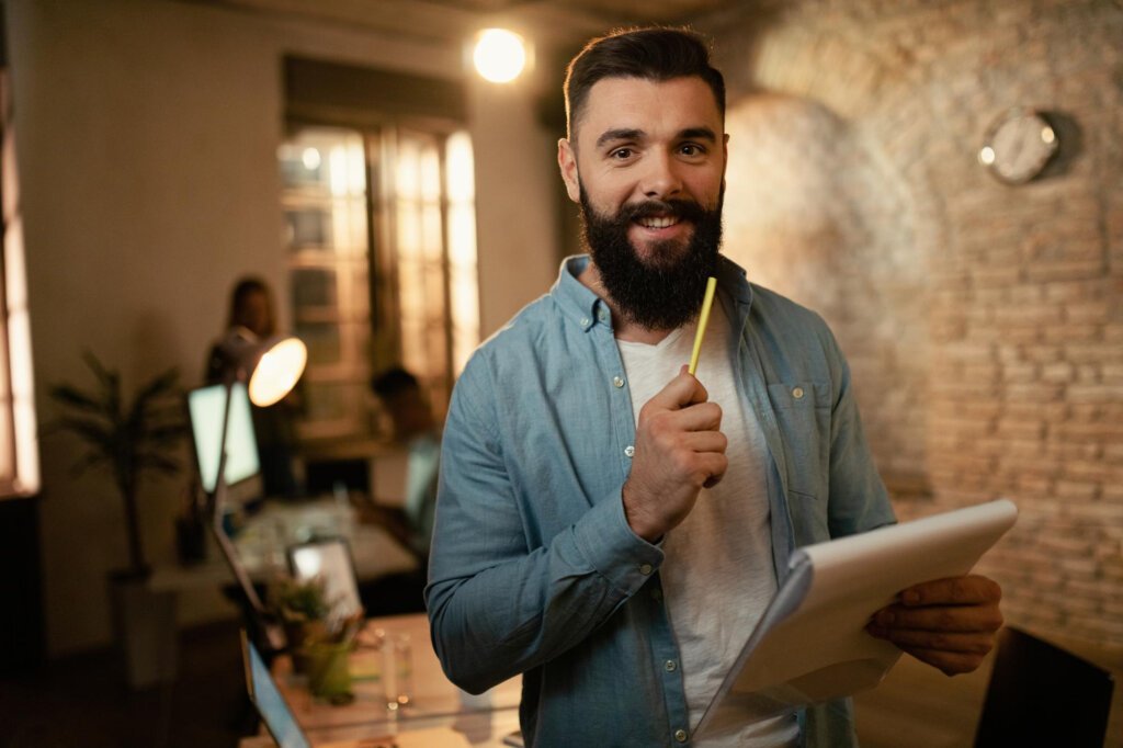 Agência Offweb Criação de Marketplaces retrato de empresario feliz analisando relatorios enquanto trabalhava ate tarde no escritorio